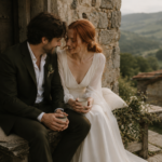 Fotografía de una pareja de novios disfrutando de un momento íntimo en una casa rural de piedra con vistas a la naturaleza. Reportaje de boda con estilo editorial, luz natural y ambiente romántico.